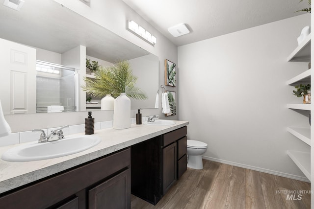 12850 Conner St, Caldwell, ID 83607 - full bathroom featuring double vanity, a shower with door, wood finished floors, toilet, and baseboards