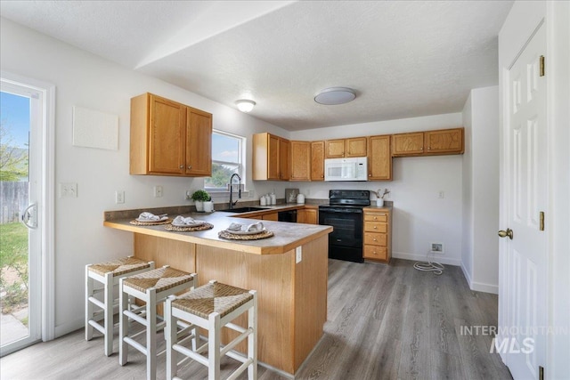 1471 Wrangler St, Twin Falls, ID 83301 - kitchen with black appliances, a sink, a peninsula, light wood-style flooring, and a textured ceiling