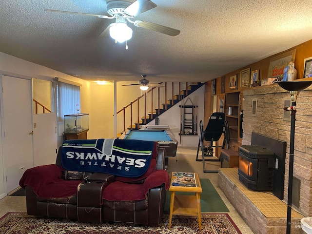 carpeted living room featuring ceiling fan, a textured ceiling, and a wood stove