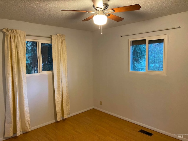 empty room with ceiling fan, hardwood / wood-style flooring, and a textured ceiling