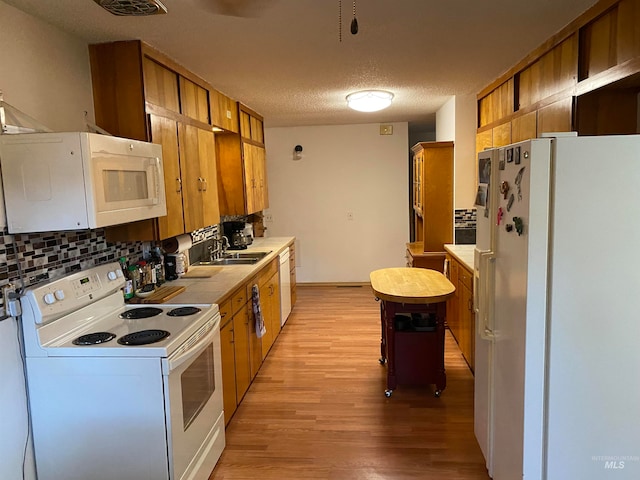 kitchen with sink, tasteful backsplash, white appliances, a textured ceiling, and light hardwood / wood-style flooring