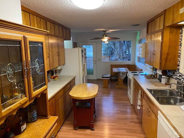 kitchen featuring sink, light hardwood / wood-style flooring, white appliances, tile countertops, and ceiling fan