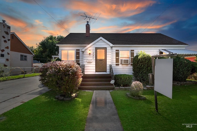 bungalow-style house featuring a lawn and cooling unit