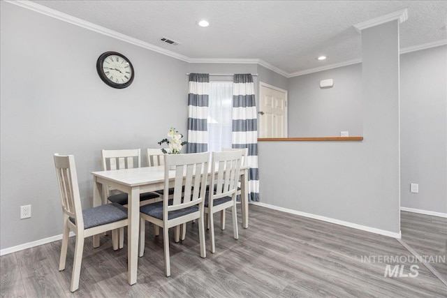 dining room with wood-type flooring, a textured ceiling, and crown molding