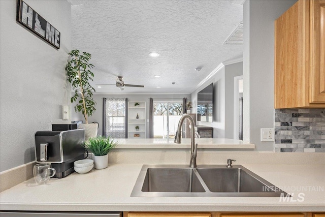 kitchen with sink, ceiling fan, ornamental molding, a textured ceiling, and decorative backsplash