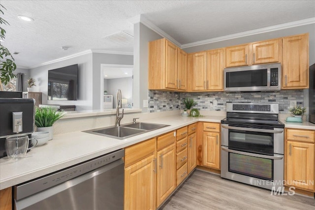 kitchen with sink, appliances with stainless steel finishes, tasteful backsplash, ornamental molding, and light hardwood / wood-style floors