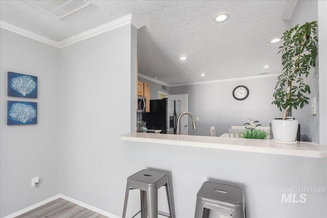 kitchen with hardwood / wood-style flooring, ornamental molding, stainless steel appliances, and a textured ceiling