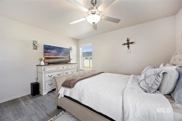 bedroom with light wood finished floors, baseboards, and a ceiling fan