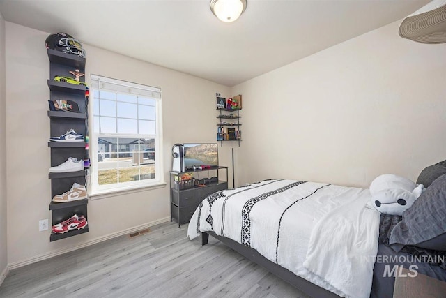 bedroom with baseboards, visible vents, and wood finished floors