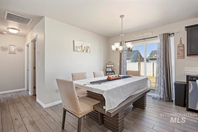 dining area featuring baseboards, an inviting chandelier, visible vents, and wood tiled floor