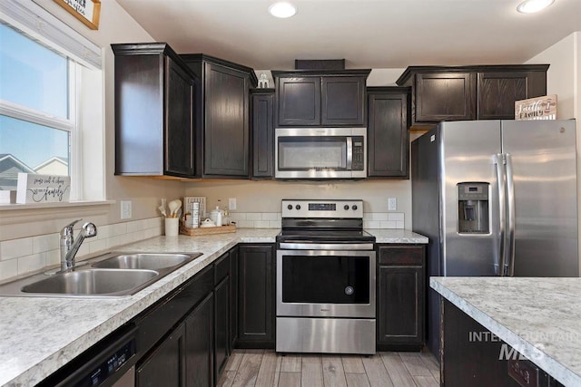 kitchen with stainless steel appliances, recessed lighting, light countertops, light wood-style floors, and a sink