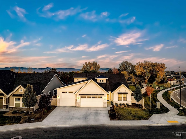 view of front of property with a garage, stone siding, driveway, and a mountain view