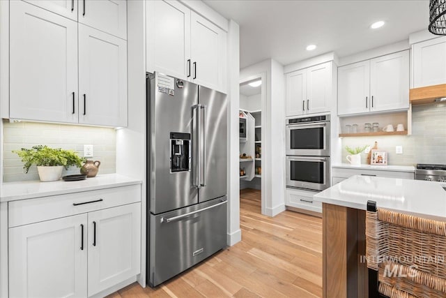 kitchen featuring open shelves, white cabinetry, stainless steel appliances, and light countertops