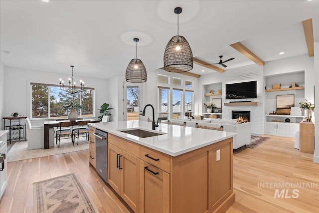 kitchen featuring light brown cabinets, a sink, open floor plan, light countertops, and a center island with sink