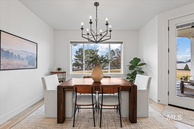 dining room featuring light wood finished floors, baseboards, and an inviting chandelier