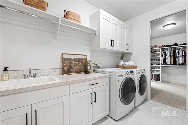 clothes washing area with washer and dryer, marble finish floor, cabinet space, and a sink