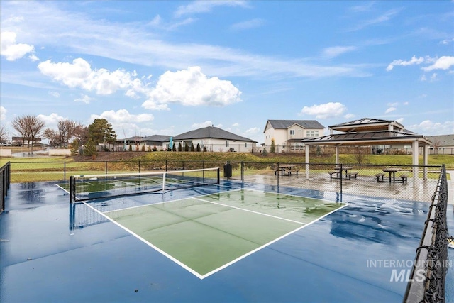 view of tennis court with a residential view, fence, and a gazebo