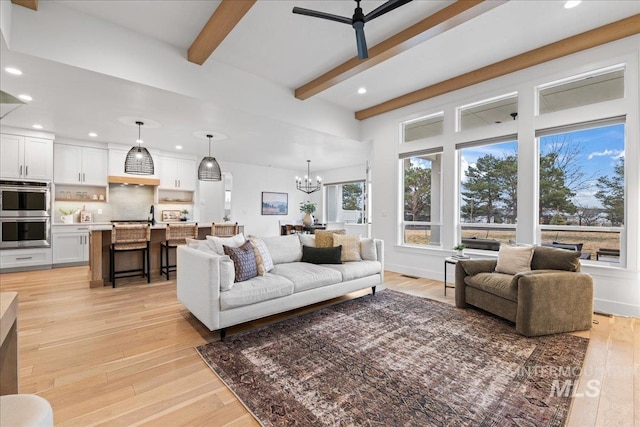 living area with recessed lighting, ceiling fan with notable chandelier, baseboards, light wood finished floors, and beamed ceiling