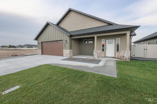 view of front of house featuring an attached garage, stone siding, driveway, a front lawn, and board and batten siding