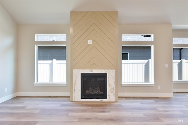 unfurnished living room featuring baseboards, a fireplace, and light wood finished floors