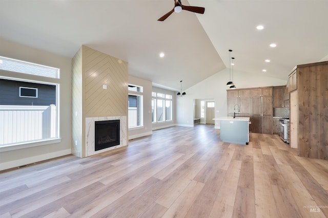 534 Falling Leaf Ln, Twin Falls, ID 83301 - unfurnished living room featuring ceiling fan, light wood-type flooring, a fireplace, a sink, and high vaulted ceiling