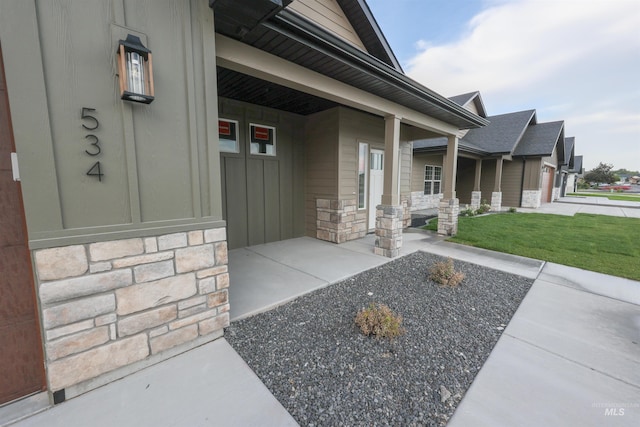 property entrance featuring stone siding, covered porch, and a yard