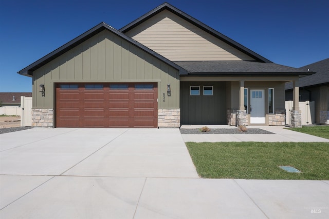 view of front of house with a garage, stone siding, and driveway