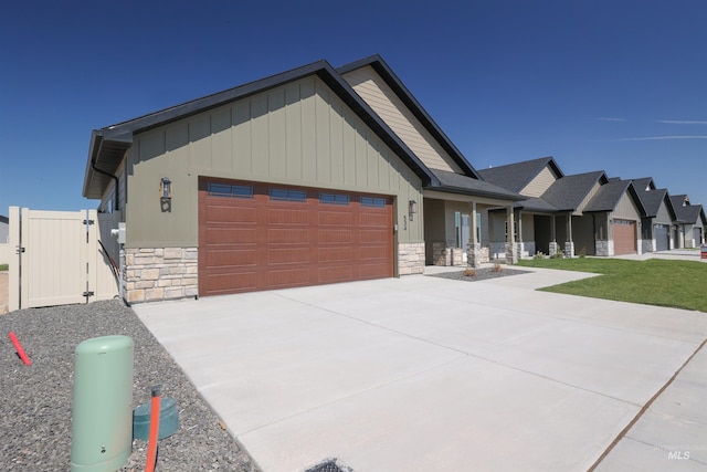 view of front of house with board and batten siding, stone siding, an attached garage, and concrete driveway