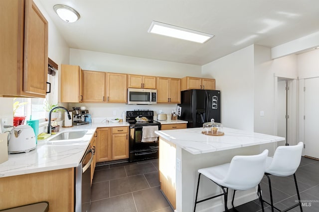 kitchen featuring a kitchen island, a breakfast bar, sink, dark tile patterned floors, and black appliances