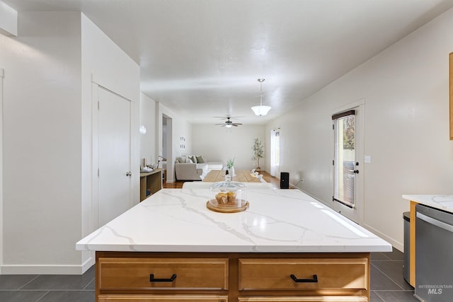 kitchen featuring pendant lighting, stainless steel dishwasher, a center island, and dark tile patterned floors