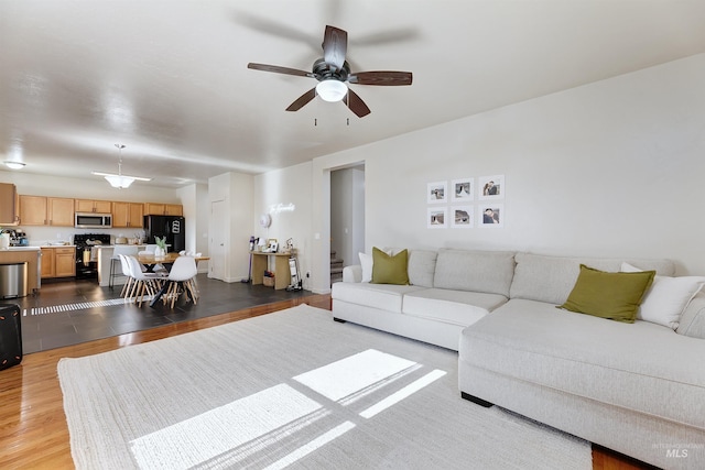 living room featuring ceiling fan and light hardwood / wood-style floors