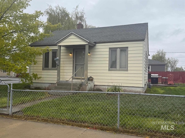 view of front of house featuring a chimney, fence private yard, a front lawn, a shingled roof, and entry steps