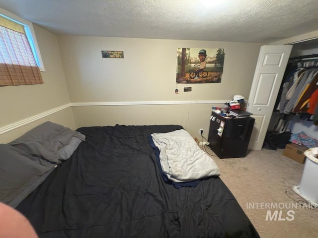 bedroom featuring carpet flooring, fridge, a textured ceiling, and a closet