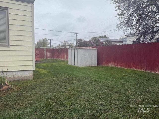 view of yard featuring a fenced backyard, a storage unit, and an outdoor structure