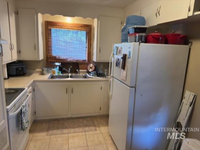 kitchen with a sink, light countertops, range with electric cooktop, freestanding refrigerator, and white cabinetry