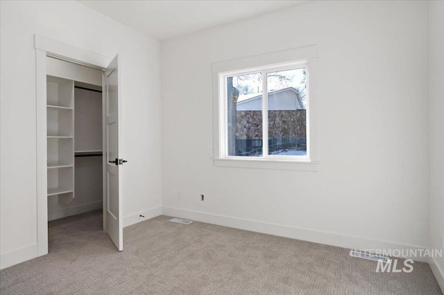 unfurnished bedroom featuring light carpet, a closet, and a walk in closet