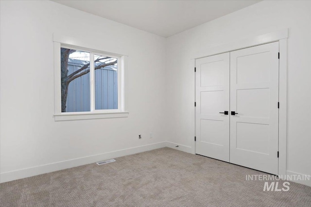 unfurnished bedroom with light carpet and a closet