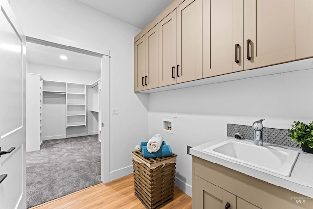 clothes washing area with light colored carpet, sink, cabinets, and hookup for a washing machine