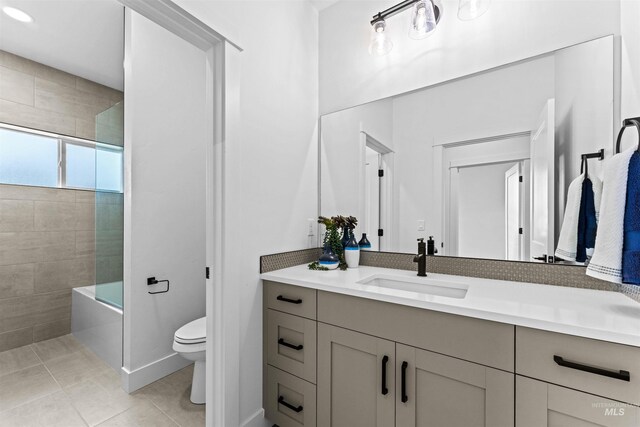 full bathroom with tile flooring, vanity, toilet, and bath / shower combo with glass door