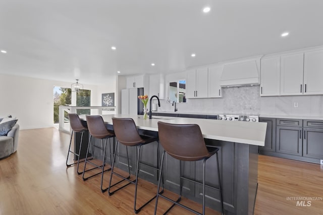 22168 Rio Vista Dr, Caldwell, ID 83607 - kitchen featuring a sink, light countertops, custom range hood, freestanding refrigerator, and a kitchen island with sink