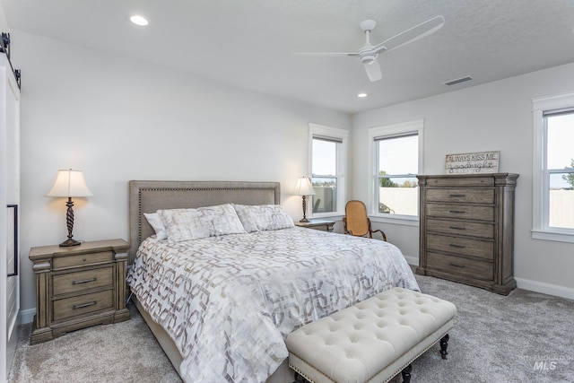 bedroom with ceiling fan, light colored carpet, and multiple windows