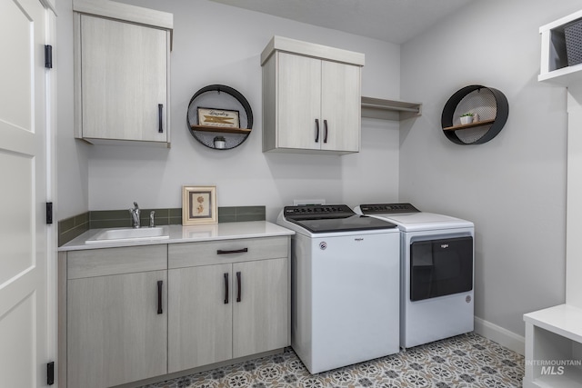 clothes washing area with washing machine and clothes dryer, sink, light tile patterned flooring, and cabinets