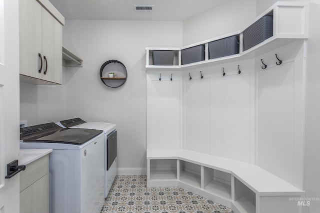 laundry area featuring cabinets, light tile patterned floors, and washer and clothes dryer