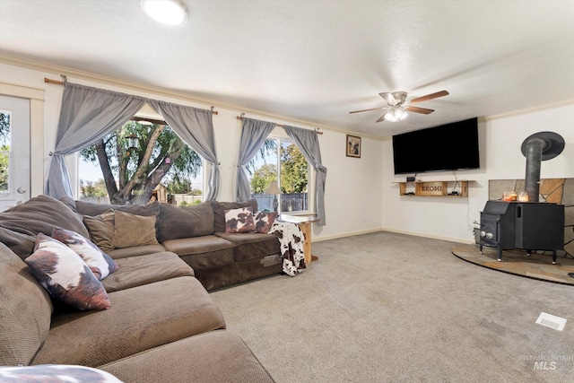 carpeted living room with crown molding, ceiling fan, and a wood stove