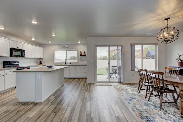 kitchen with light hardwood / wood-style floors, white cabinets, electric range, and plenty of natural light