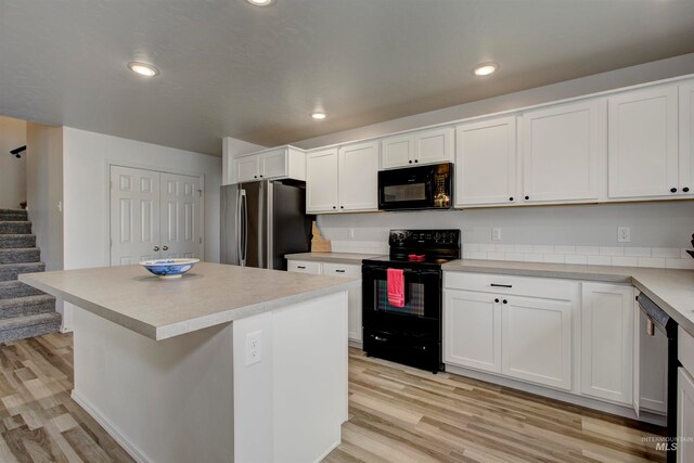 kitchen featuring white cabinetry, light hardwood / wood-style floors, black appliances, and a kitchen island