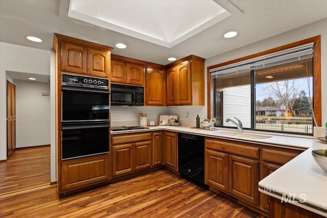 kitchen featuring a sink, black appliances, brown cabinetry, and light countertops