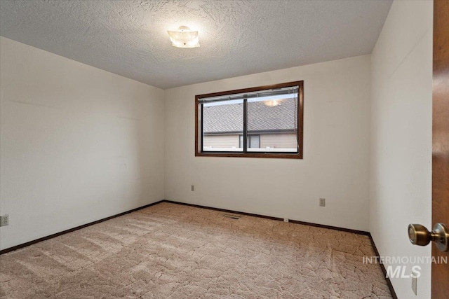 empty room featuring baseboards, carpet floors, a textured ceiling, and visible vents