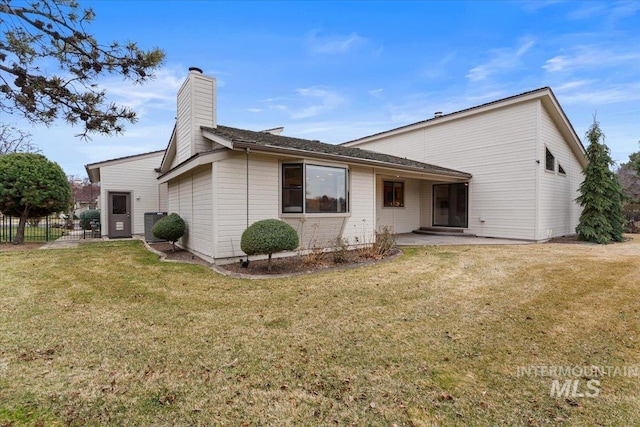 back of property featuring a patio area, a chimney, a yard, and fence