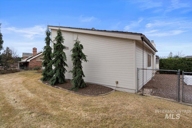 view of property exterior with a gate, fence, and a lawn